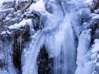 Wasserfall in Becken umgeben von Eisgebilden